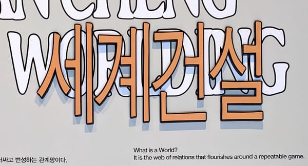 "WORLDING"과 "세계건설"이라는 문구 아래 "What is a World? It is the web of relations that flourishes around a repeatable game."이라고 적혀 있다.